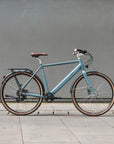 Light blue bicycle with brown tires against a gray wall