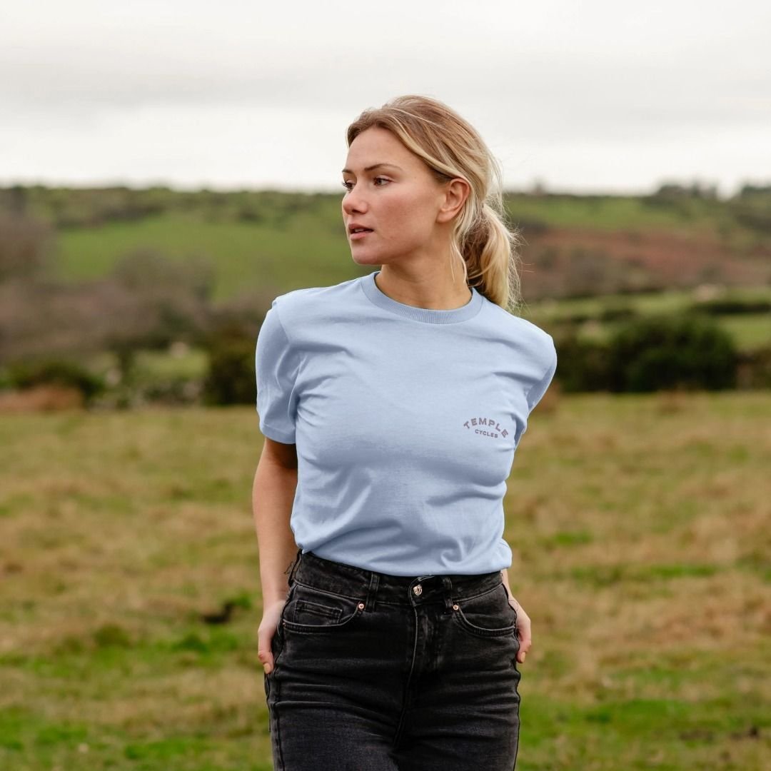 Baby blue, good quality graphic tee on female model, rural setting.
