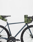 Durable roll-up bike bags attached to a lightweight, steel bike, studio setting.