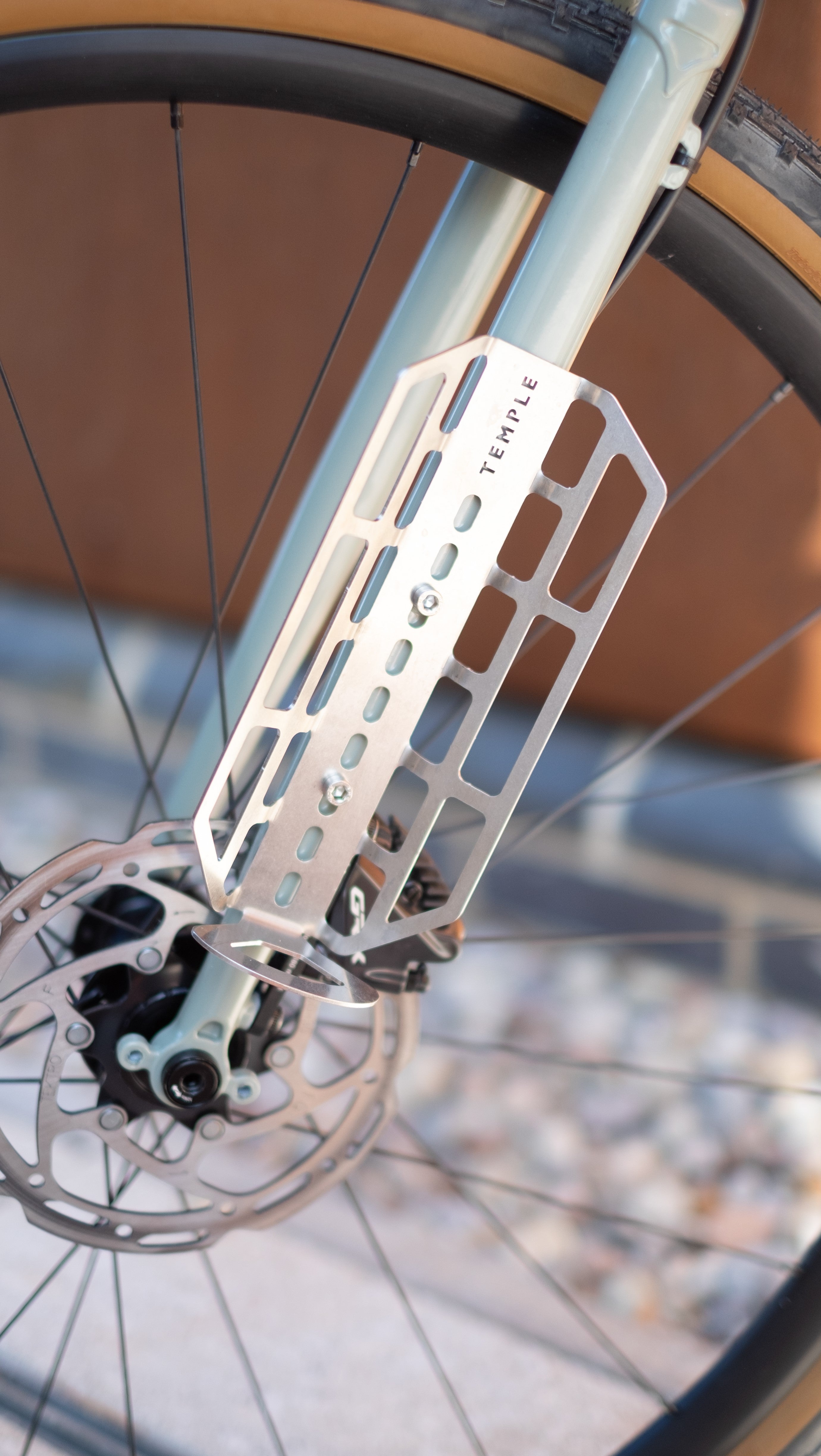 Cargo cage mounted to fork eyelets on an adventure bike with disc brakes and tan wall tyres.
