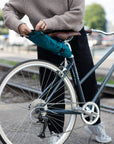 Model unrolling women’s waterproof saddle bag, urban setting.