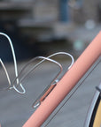 Pair of stainless steel bottle cages mounted on a pink Temple Cycles bike.