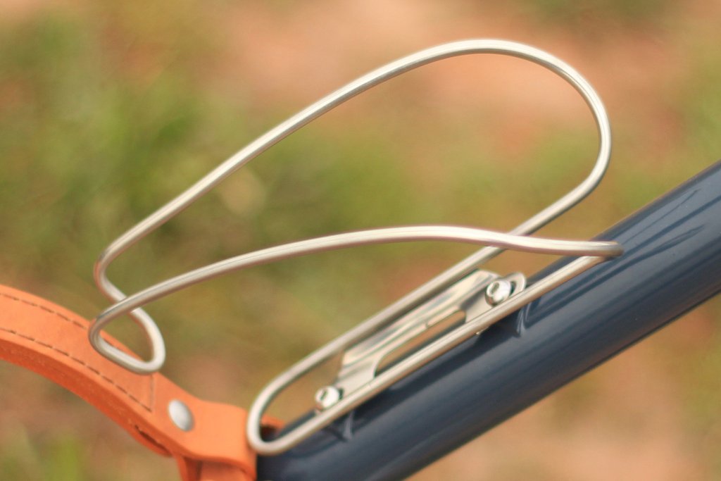 Close-up of stainless steel bottle cage mounted on a navy Temple Cycles bike.