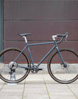 Blue steel gravel bike in an urban setting.