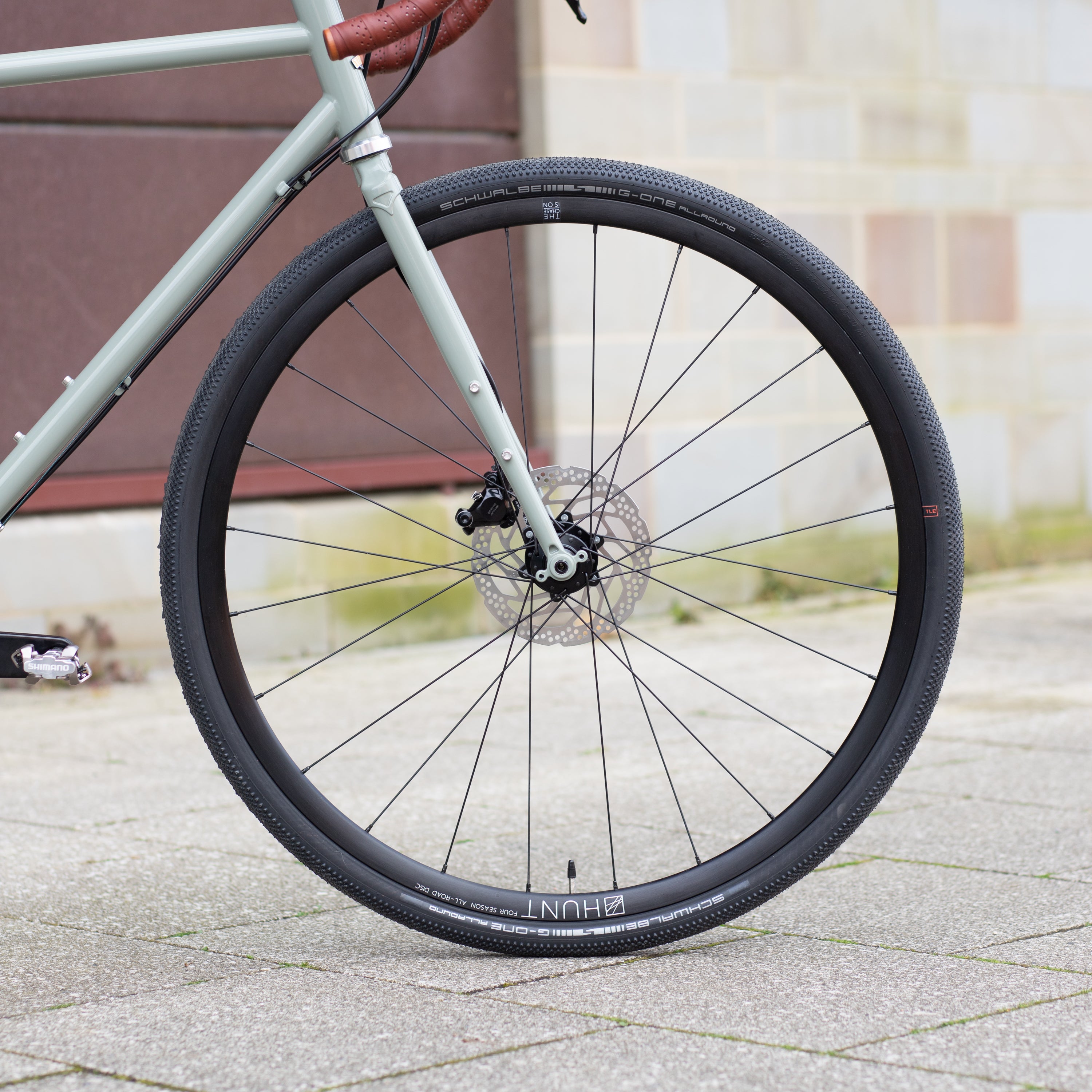 Front wheel handbuilt by Hunt on a green, lightweight steel bikepacking bike.