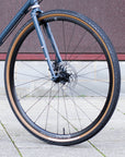 Front wheel hand built by Hunt | Tubeless Panaracer tyre on blue steel gravel bike in an urban setting.