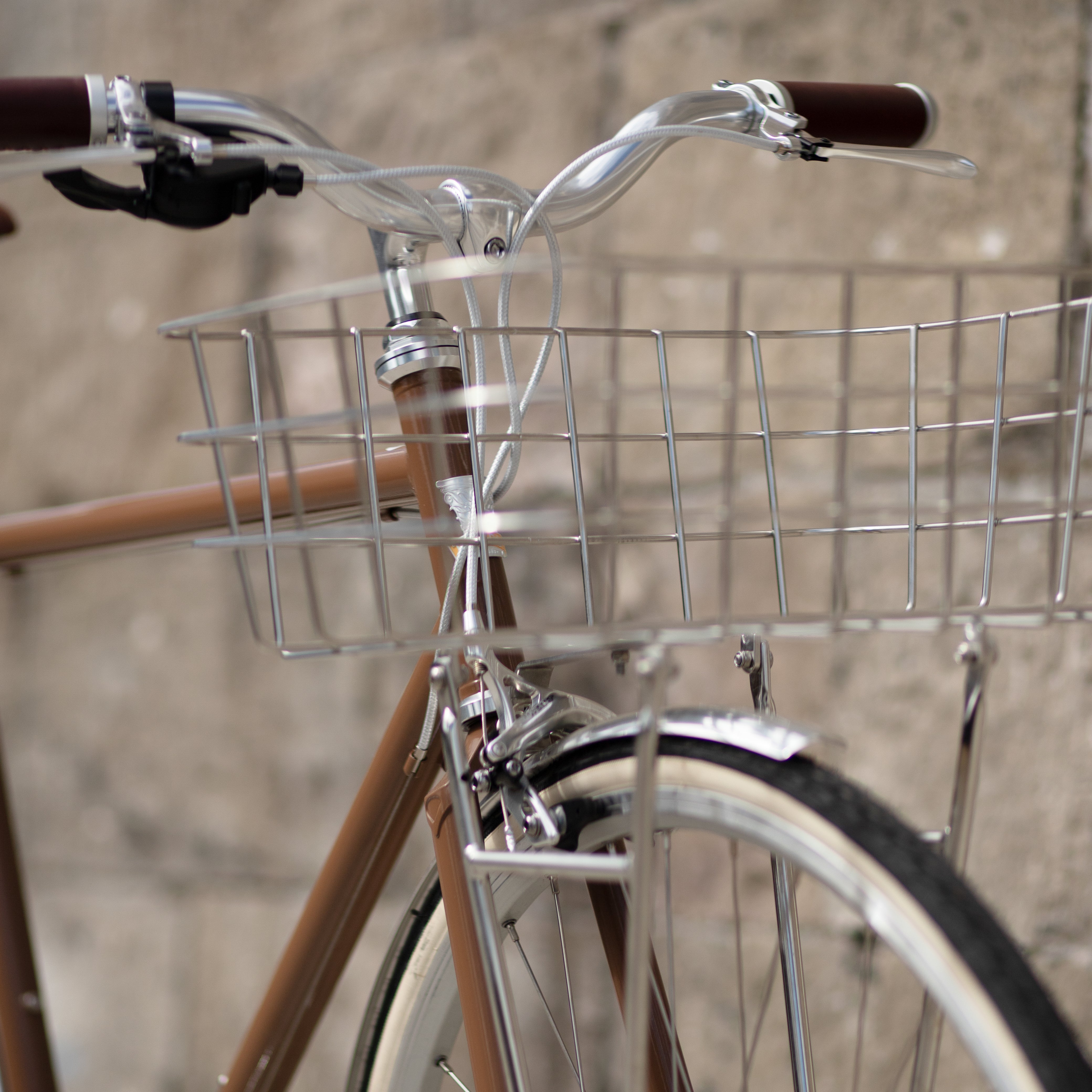 Front-on close-up shot of a stainless steel Pelago front bike basket mounted on a brown Temple Cycles bike.