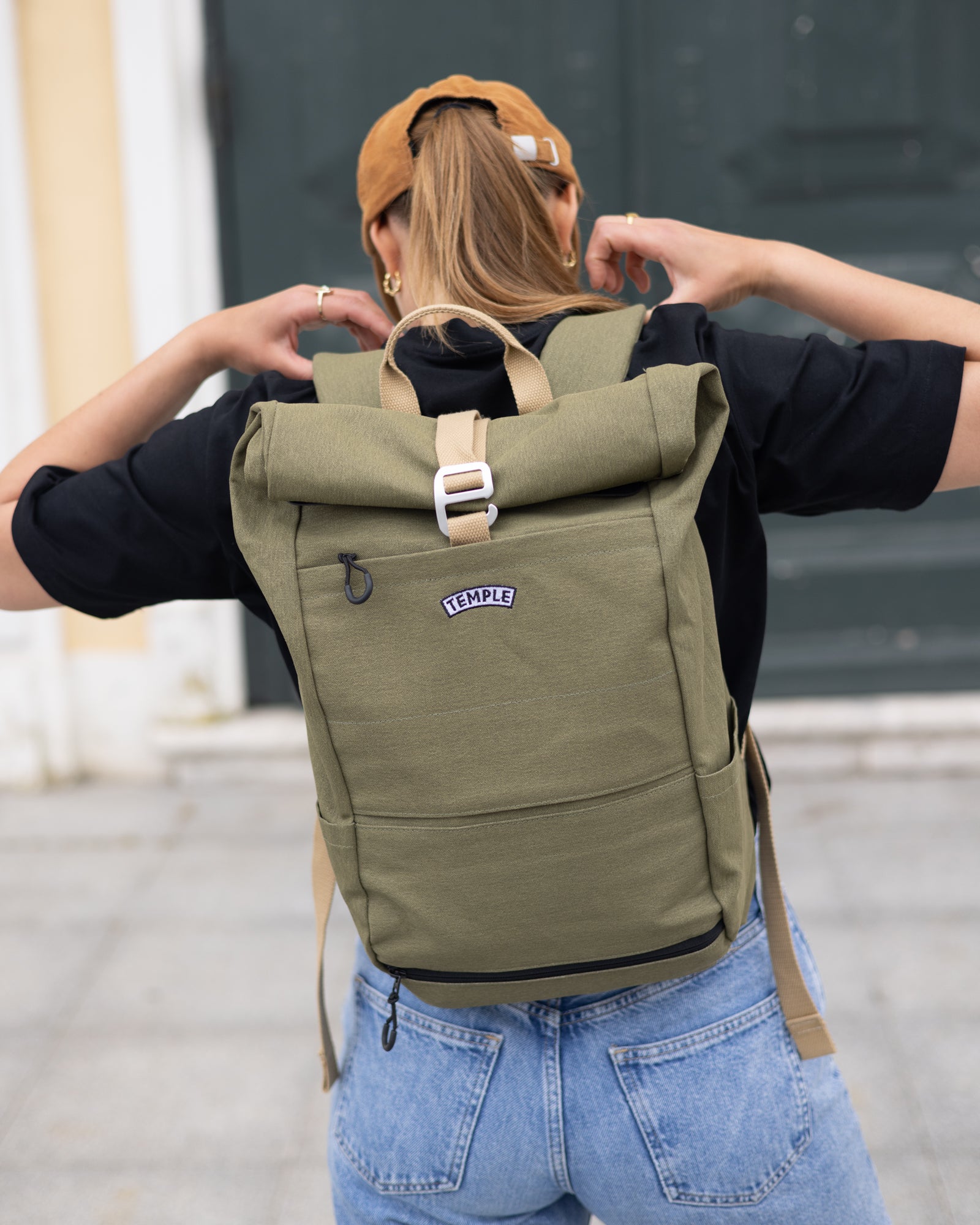 Person wearing Temple Cycles Lichen Green weather-proof pannier roll-top backpack.