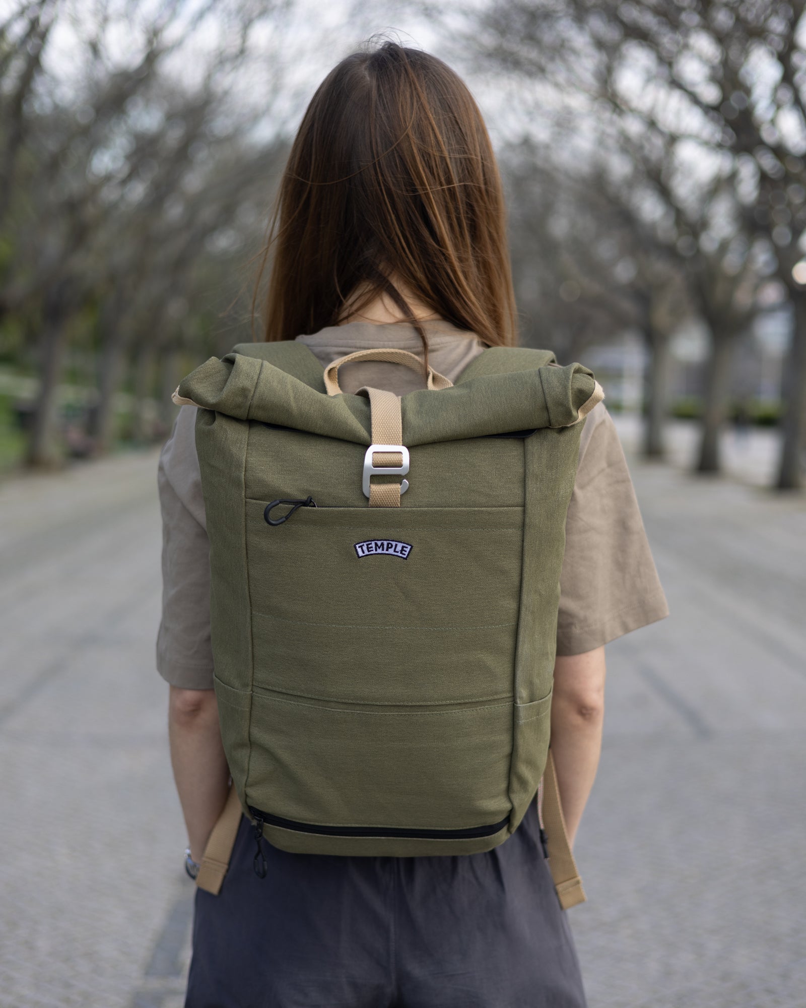 Model wearing a Temple Cycles pannier weather-proof roll-top backpack outside.