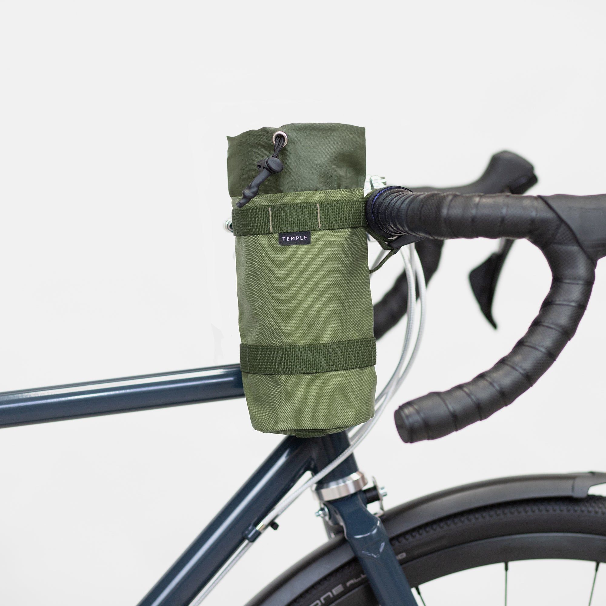 Green, un-rolled snack bag attached to a Temple bike, studio setting.