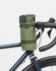 Green, un-rolled snack bag attached to a Temple bike, studio setting.
