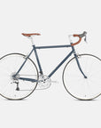 Green, steel-framed bikepacking bike in a studio setting.