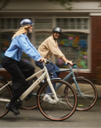 Two people riding bicycles on a city street with a blurred background