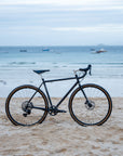 Bicycle on a sandy beach with ocean and boats in the background