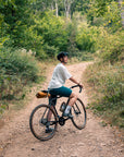 Person riding a bicycle on a dirt path in a forest