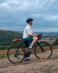 Person on a bicycle overlooking a scenic landscape with trees and fields.