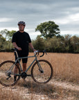 Man standing with a bicycle in a field on a cloudy day