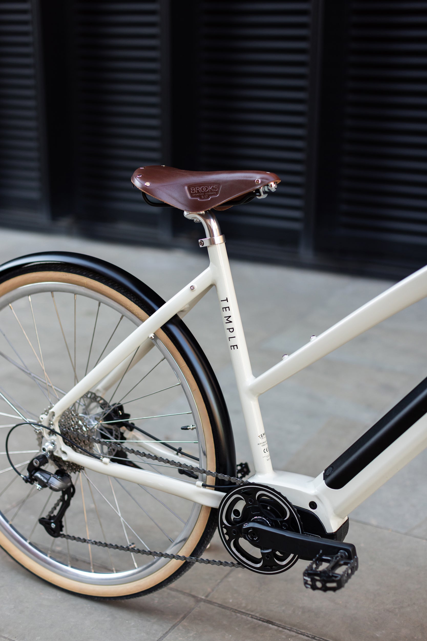 Rear wheel, with wide-ranging Shimano gears on a minimalist cream electric bicycle.