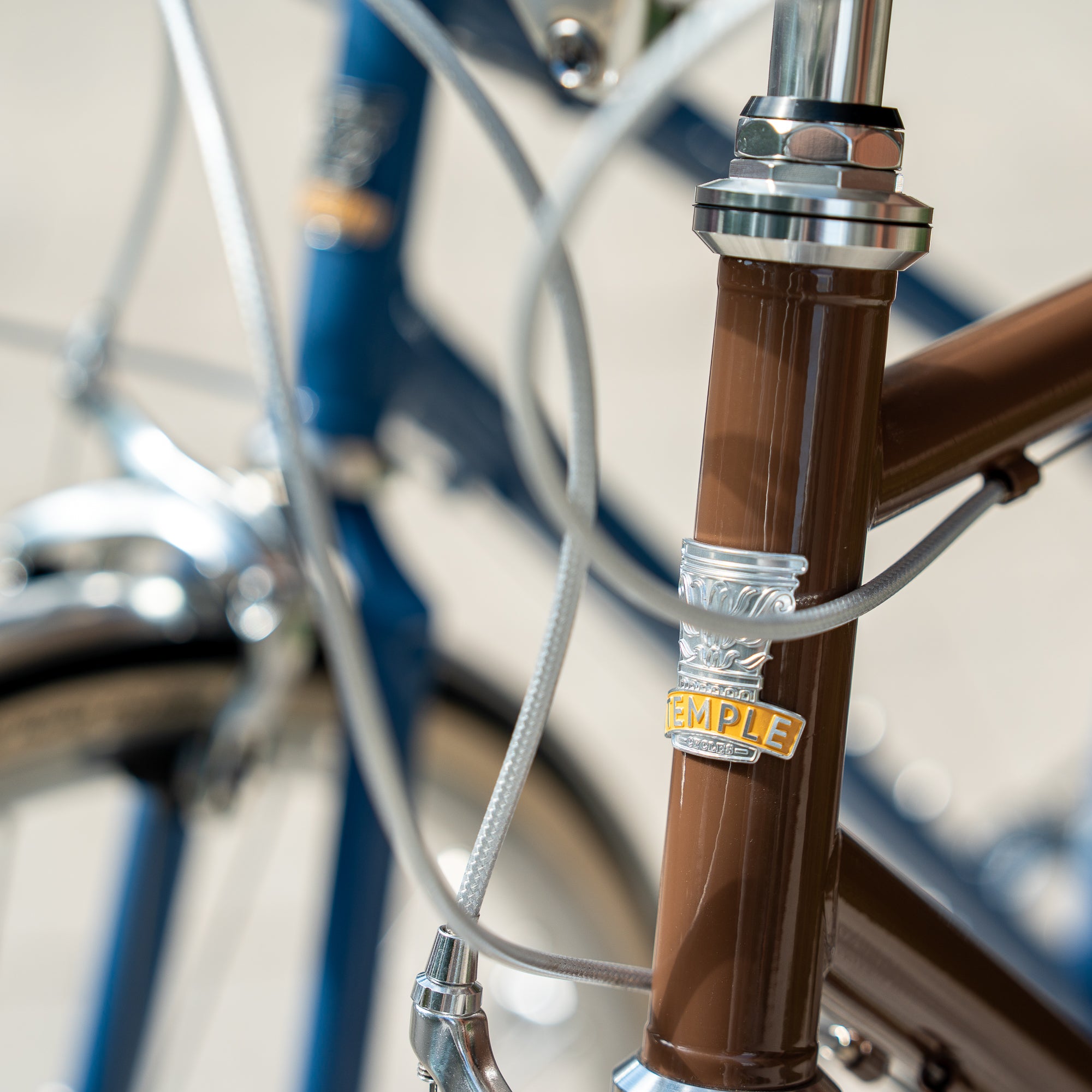 Close-up of Temple Cycles badge mounted on the front of a brown steel framed bike.