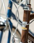 Close-up of Temple Cycles badge mounted on the front of a brown steel framed bike.