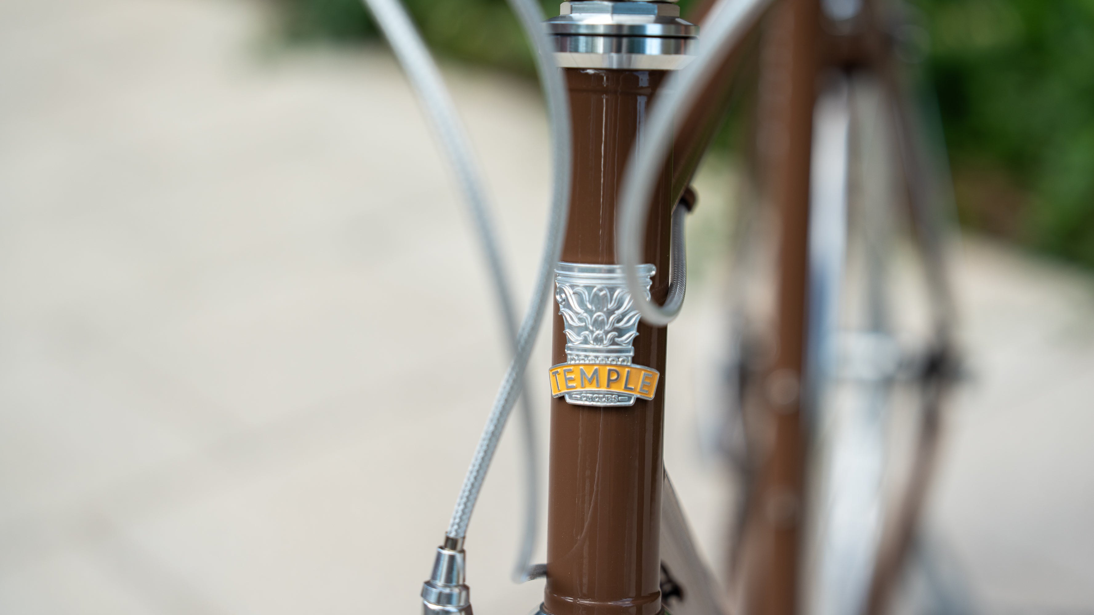 Front-on close up shot of a Temple Cycles badge on a brown steel framed bike.