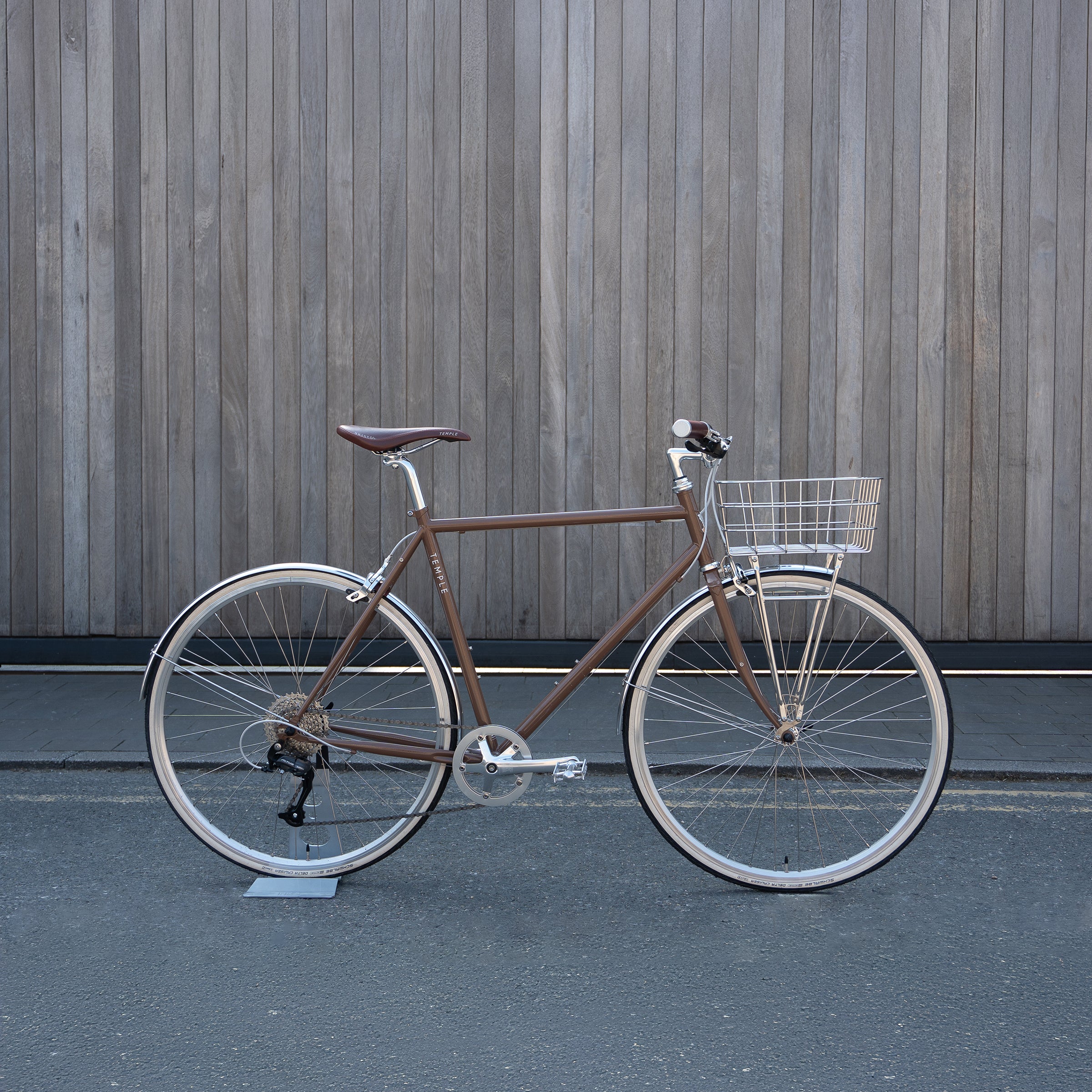 Side view of a brown Temple Cycles bike fitted with a stainless steel Pelago front basket.