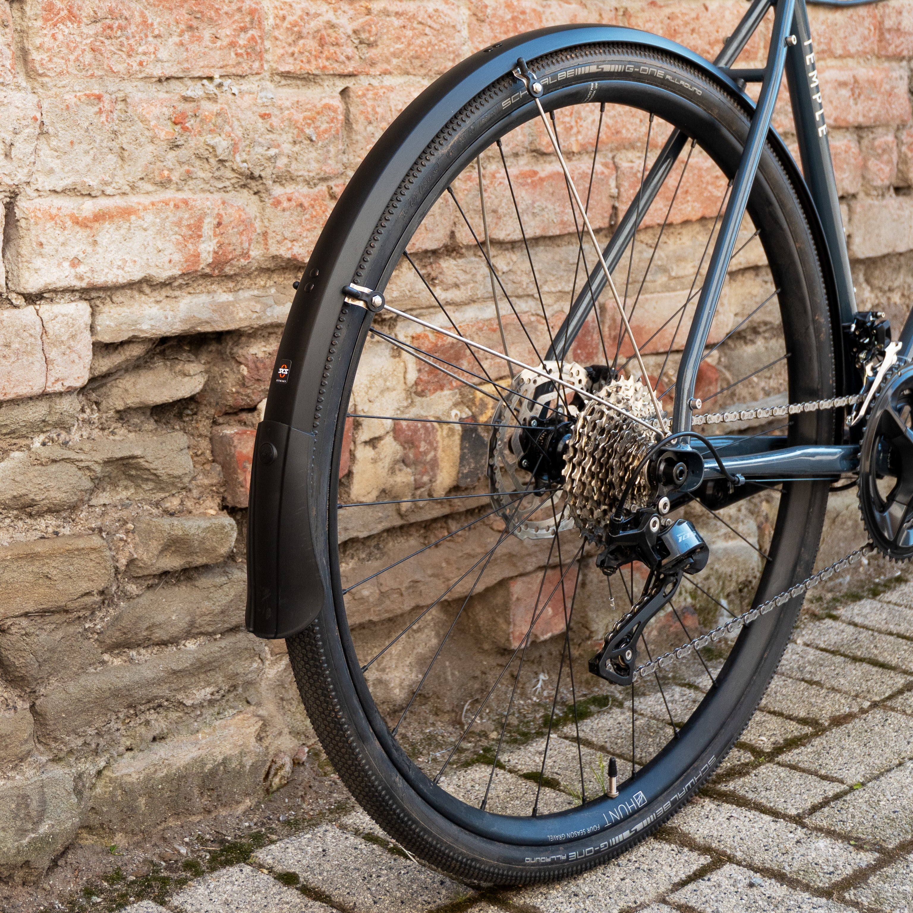 Wheel of a bicycle fitted with a black mudguard.