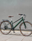 Green bicycle parked on a sidewalk against a gray wall