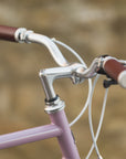 Classic handlebars on a pink steel-framed touring bike.