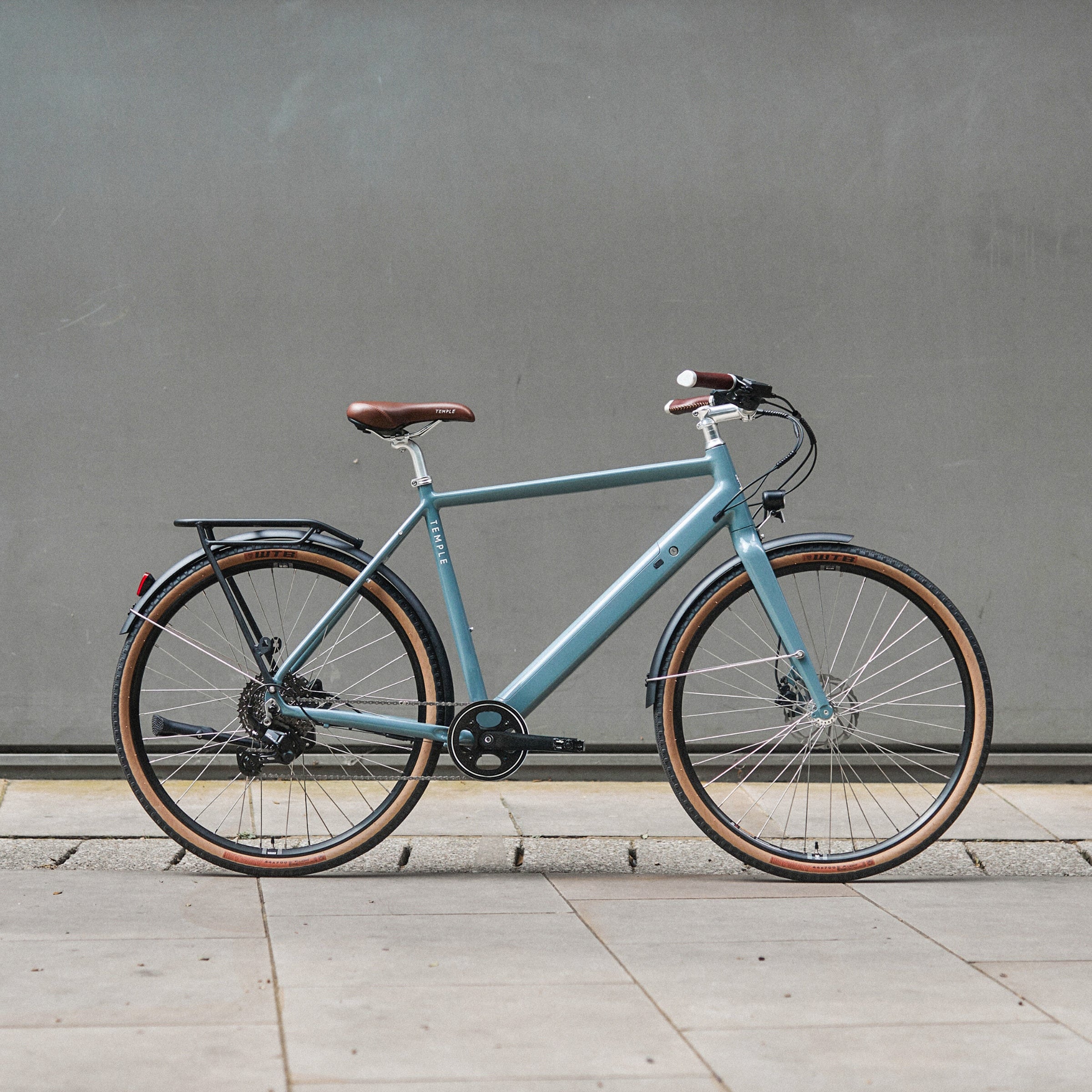 Light blue bicycle with brown tires against a gray wall