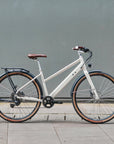 White bicycle with brown seat and tires against a gray wall
