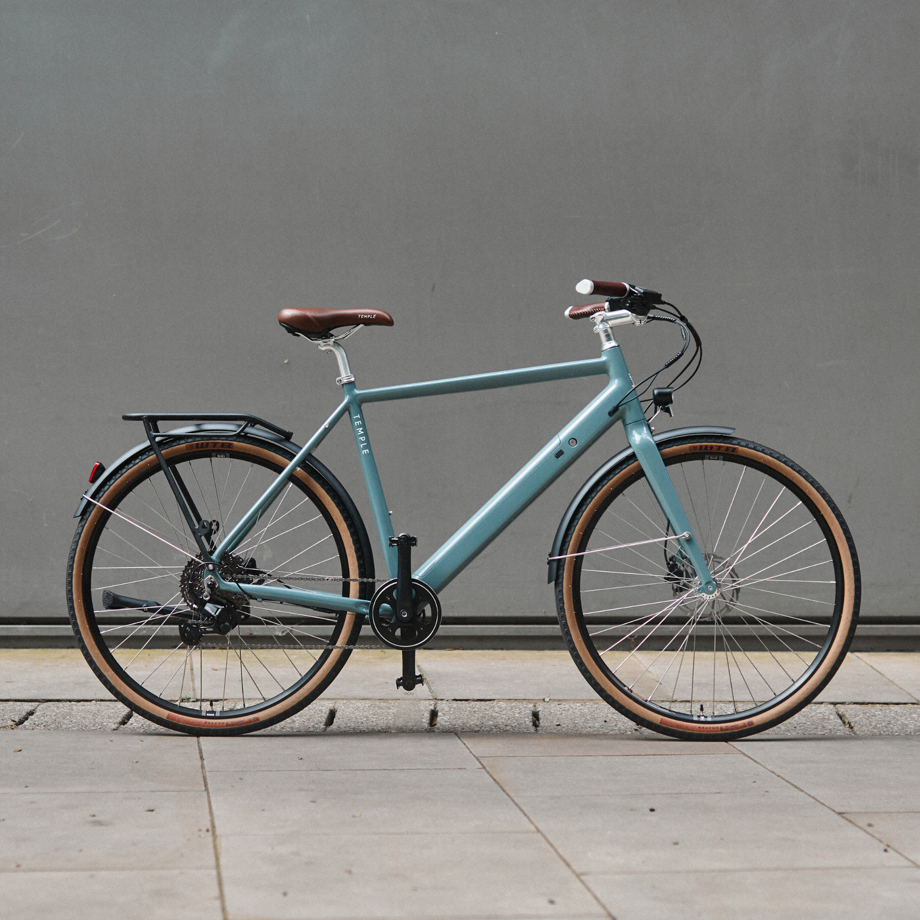 Light blue bicycle with brown tires against a gray wall