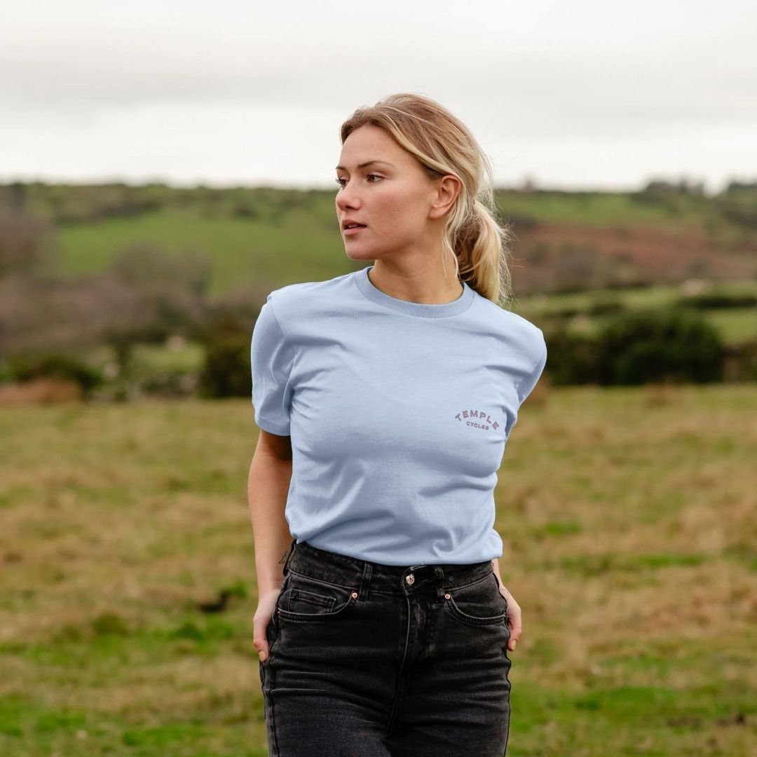 Baby blue, good quality graphic tee on female model, rural setting. 