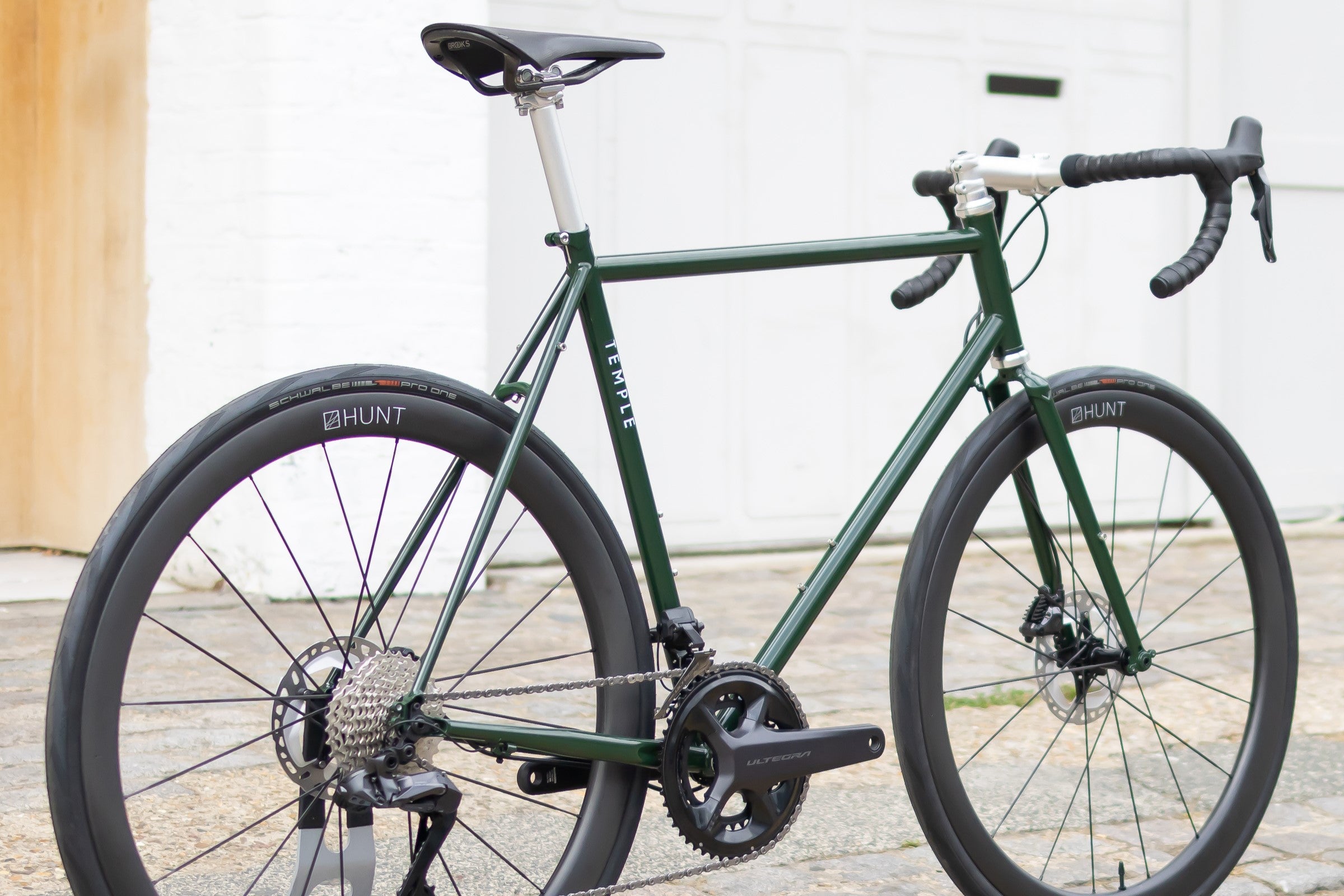 Rear view of a dark green functional steel road bike, urban setting.