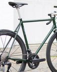 Rear view of a dark green functional steel road bike, urban setting.