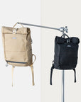 Two Pannier, roll-top backpacks in black and beige, studio setting.