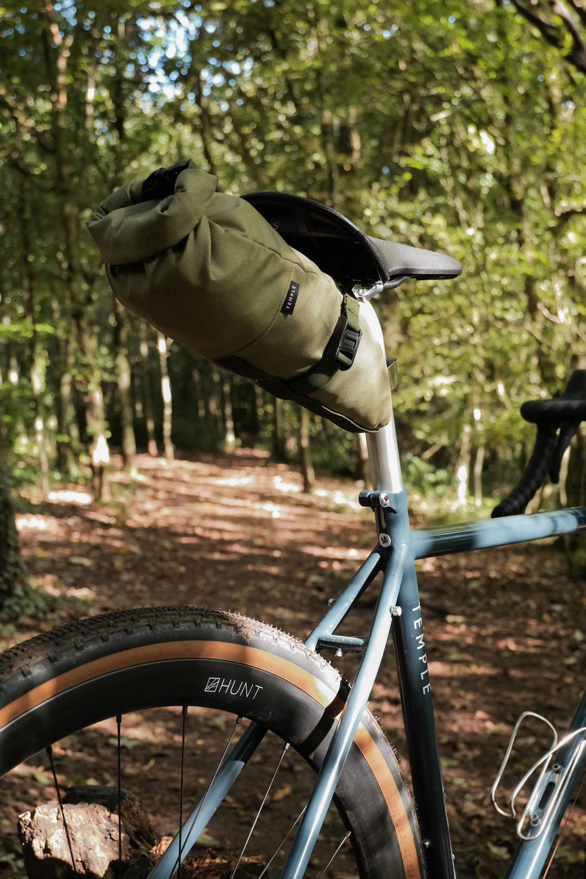 Touring bike with olive green saddle bag attached, forest setting.