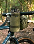 Fastened green snack bag attached to bike handlebars with a waterproof bar bag.