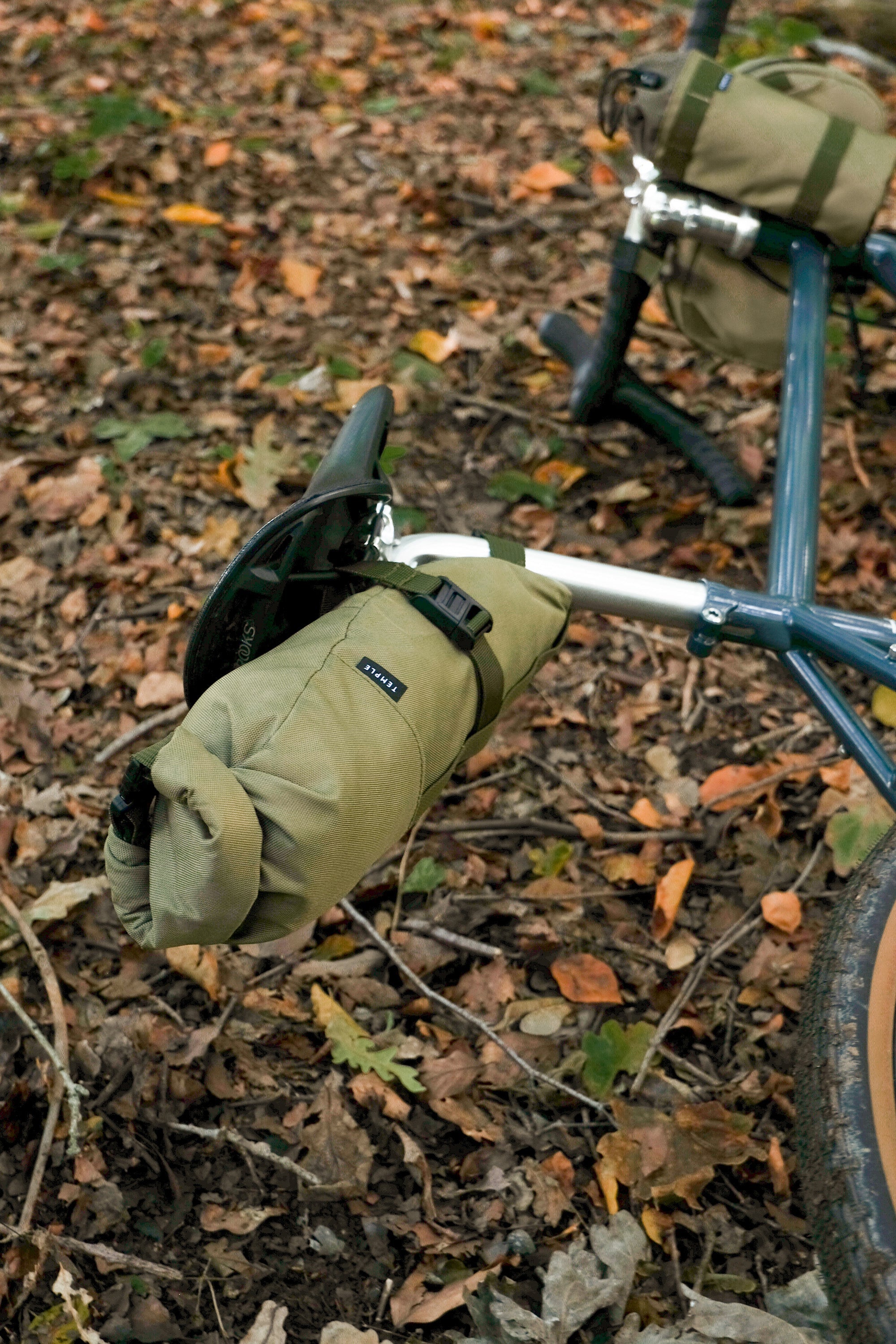 Bikepacking bicycle laying with three waterproof travel bags attached, rural setting.