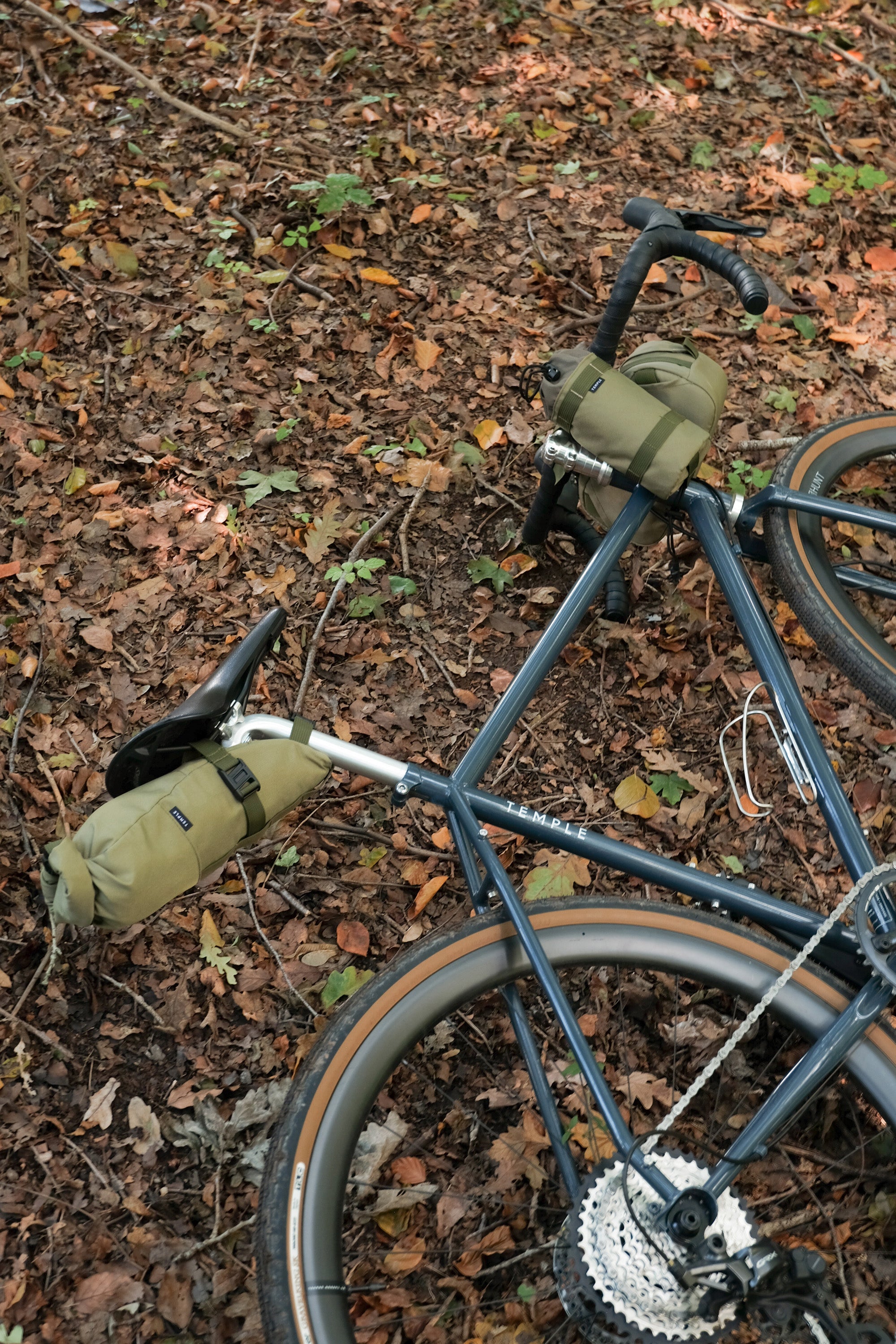 Three bike touring bags attached to hybrid bike, forest floor setting.