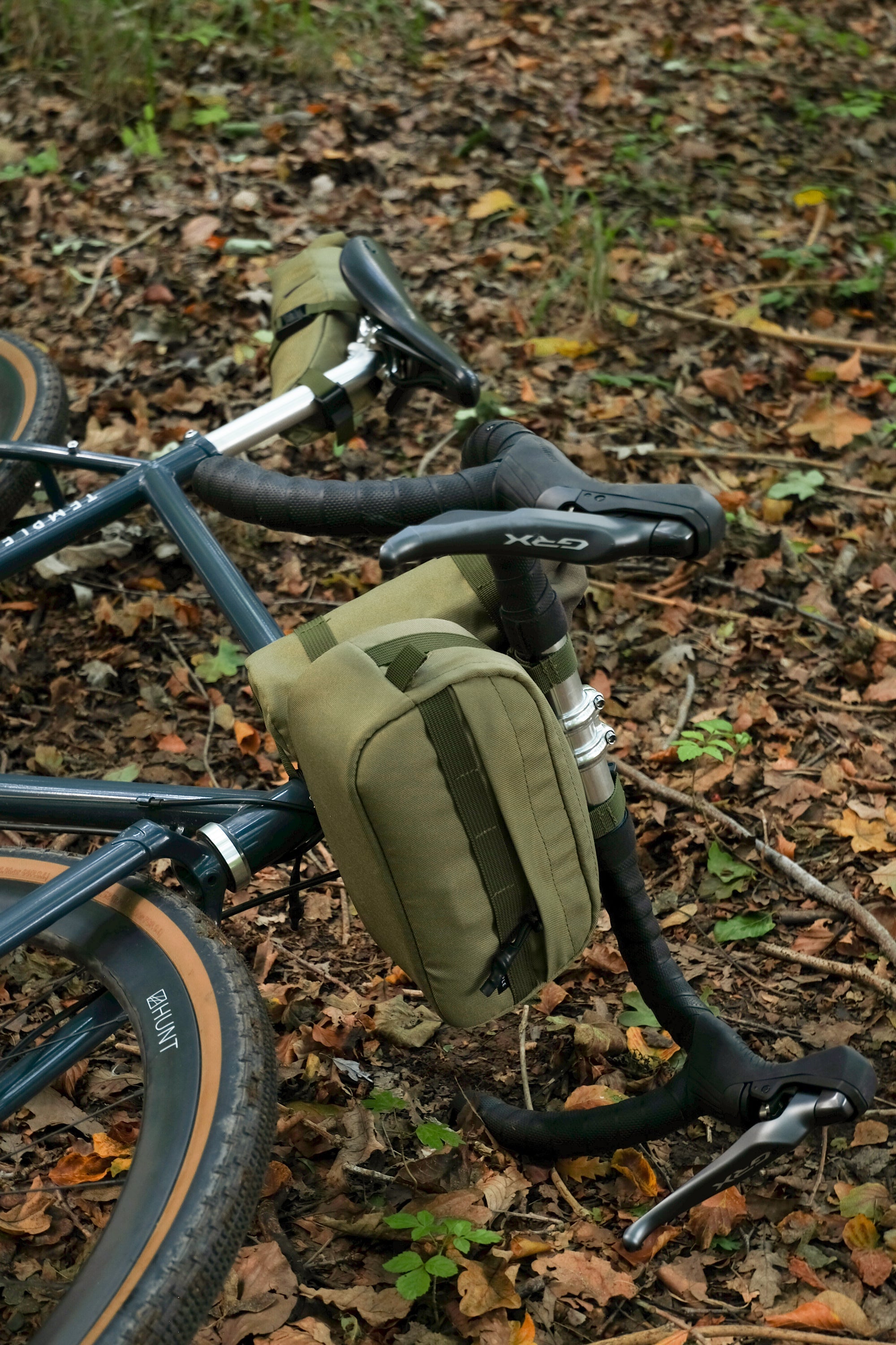 Bike laying on forest ground with three waterproof bike bags attached.