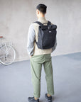 Model wearing black pannier backpack in an urban setting.