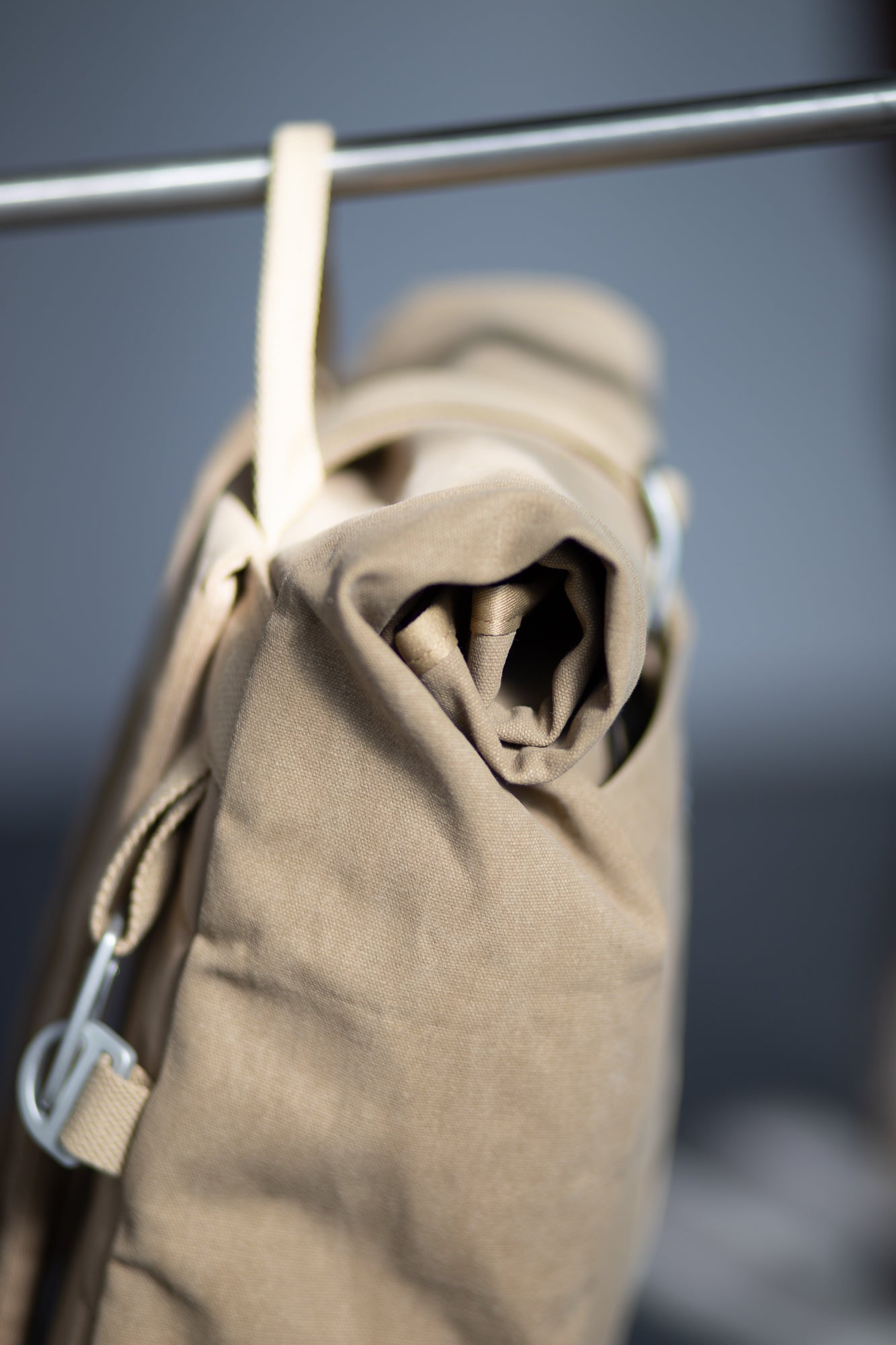 Waterproof beige pannier bag hanging in a studio setting.