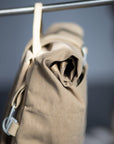 Waterproof beige pannier bag hanging in a studio setting.