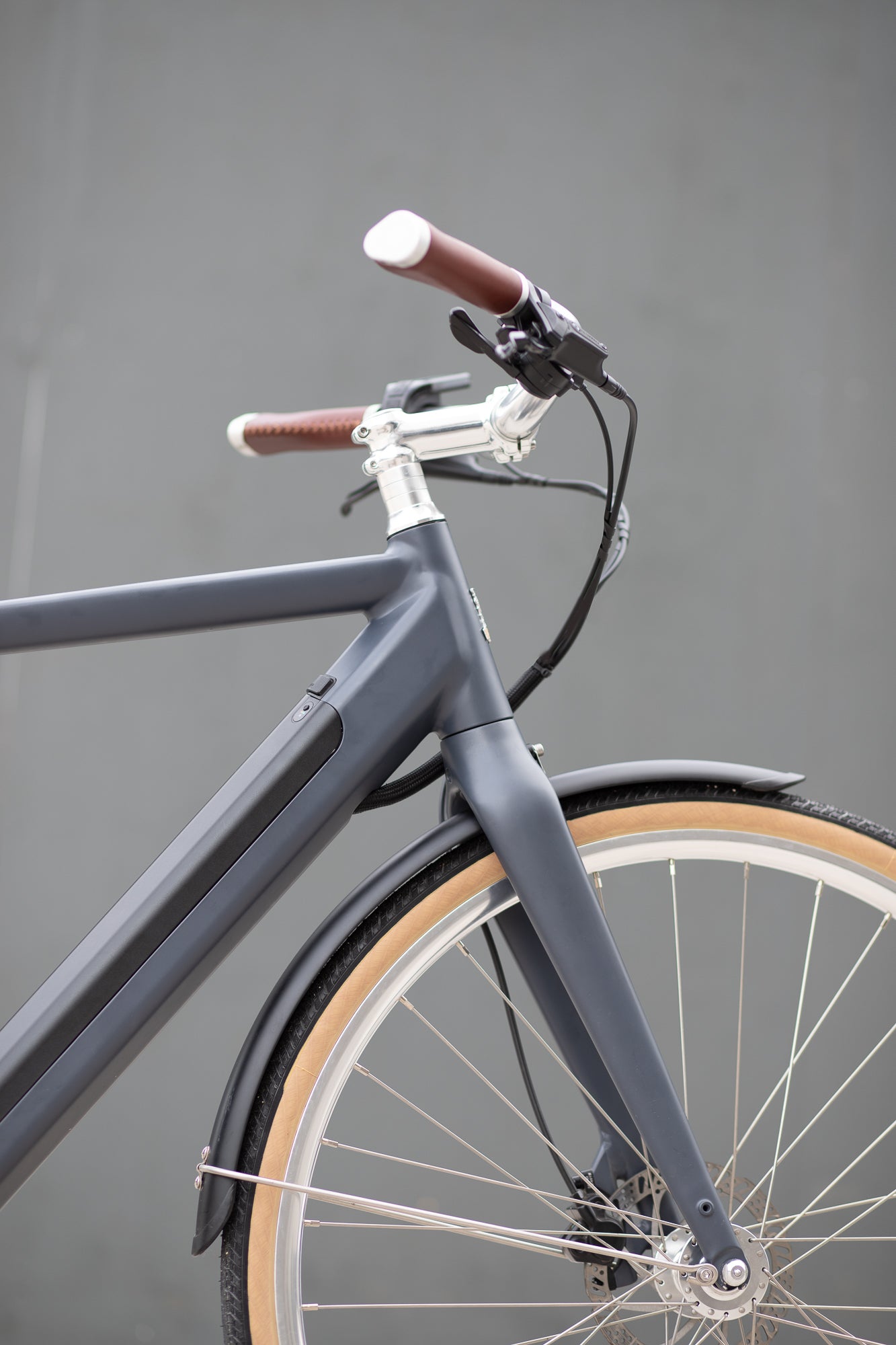 Front wheel, premium silver swept handlebars and minimalist Samsung battery on a classic electric bike. 