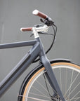 Front wheel, premium silver swept handlebars and minimalist Samsung battery on a classic electric bike. 