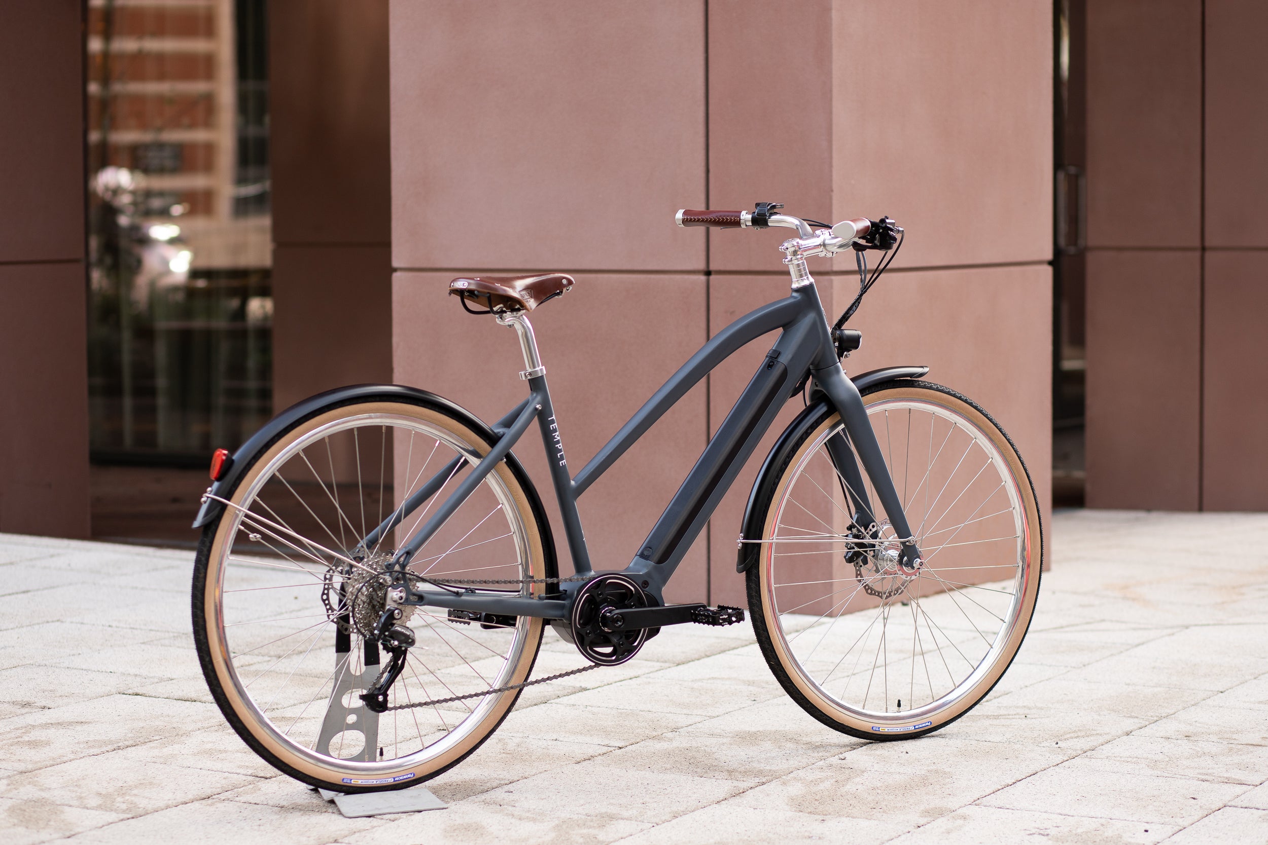 Step Through electric dark blue bike, urban setting. 