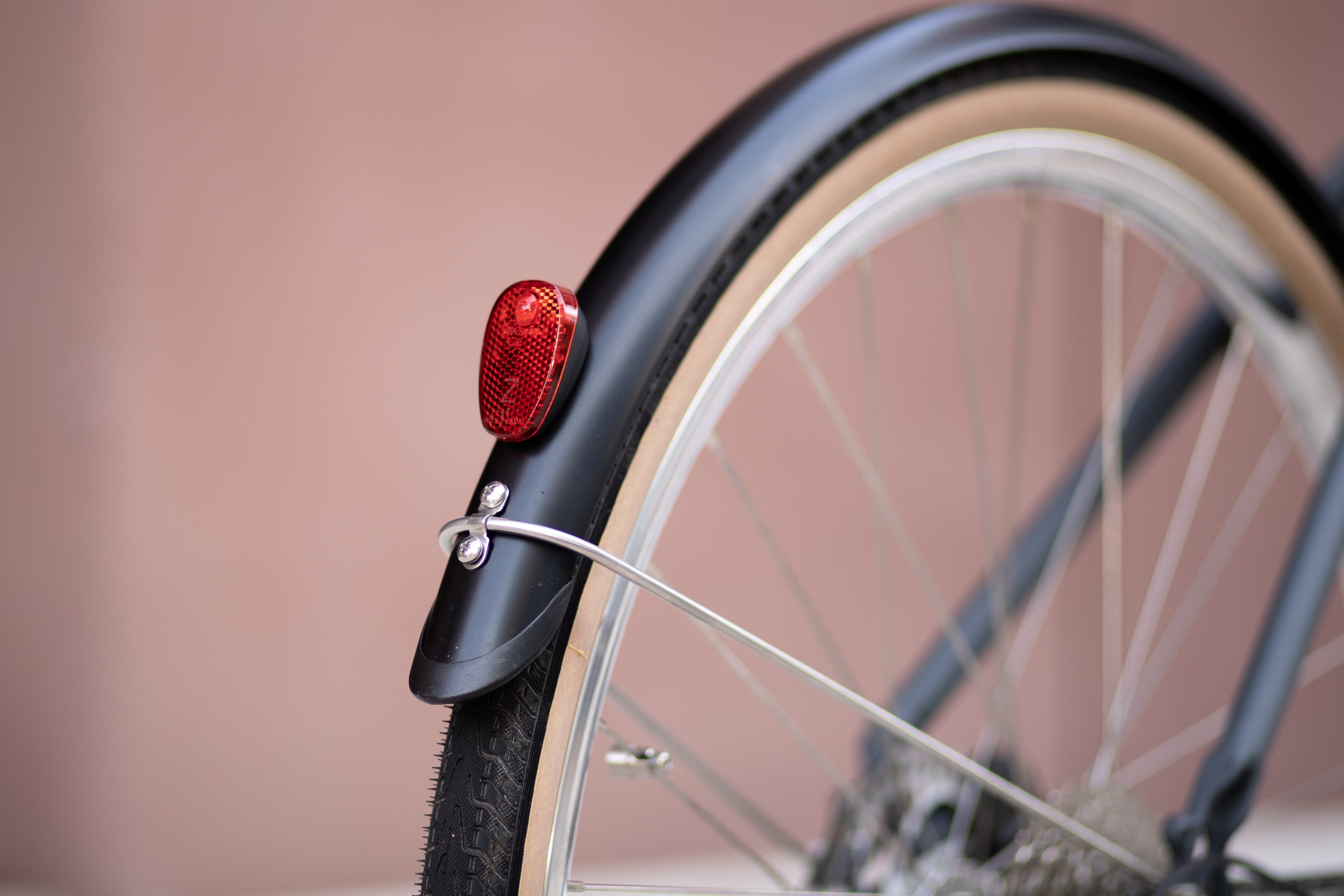 Rear bike wheel with full length Temple mudguards and red light reflector on a Step Through e-bike.