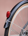 Rear bike wheel with full length Temple mudguards and red light reflector on a Step Through e-bike.