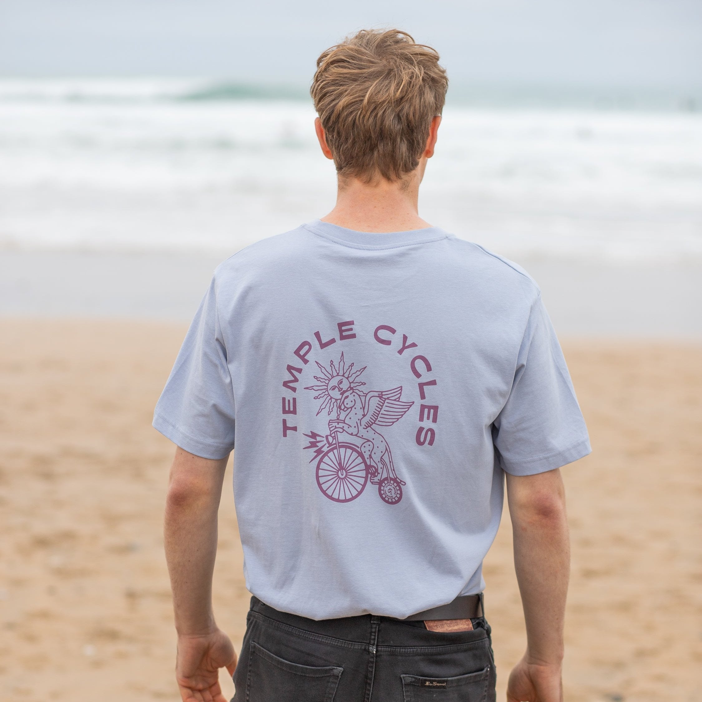 Unisex cotton tee in light blue, beach setting.